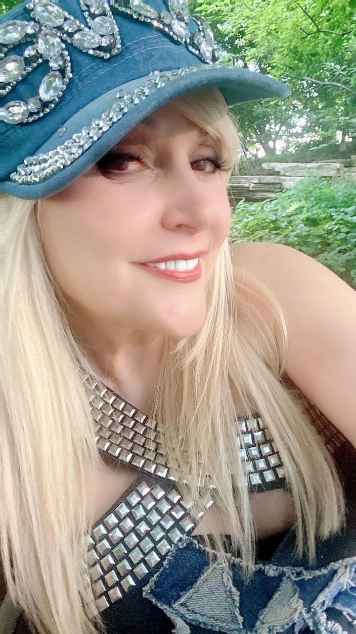 A woman wearing a blue hat and a necklace is smiling.