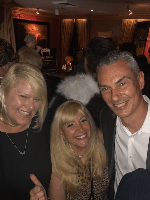 A man and two women are posing for a picture in a crowded room.