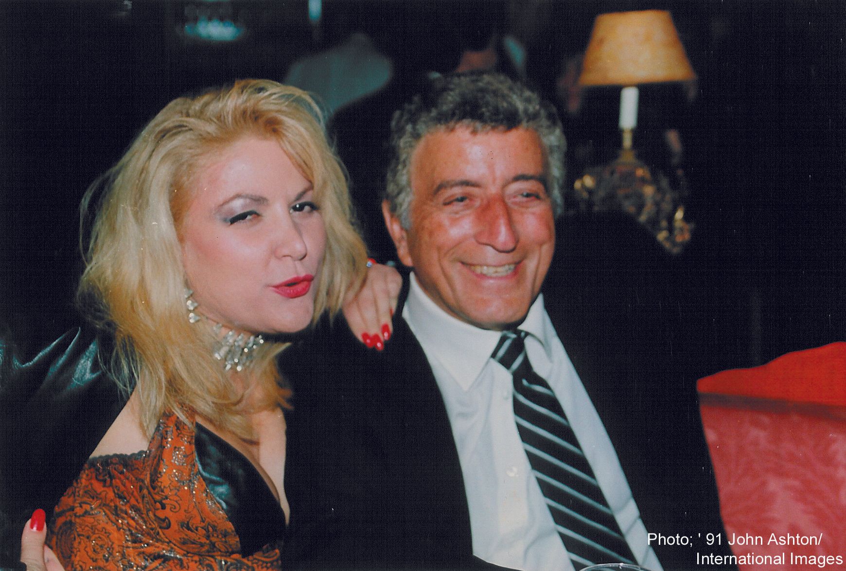 A man and a woman are posing for a picture and the man is wearing a suit and tie