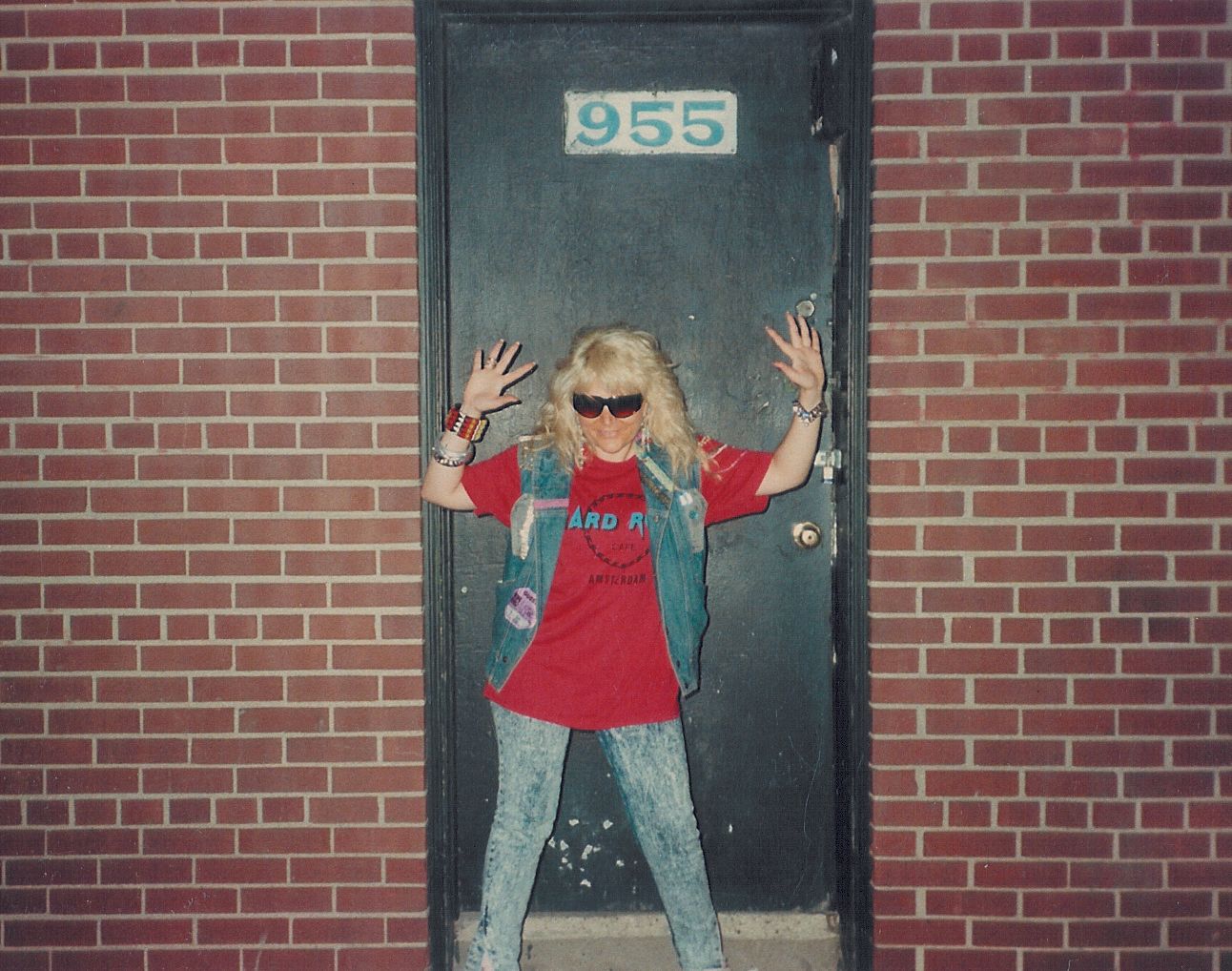 A woman standing in front of a door with the number 955 on it