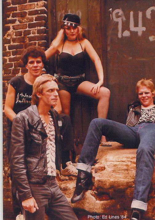 A group of people posing in front of a brick wall that says ' 9.4 ' on it