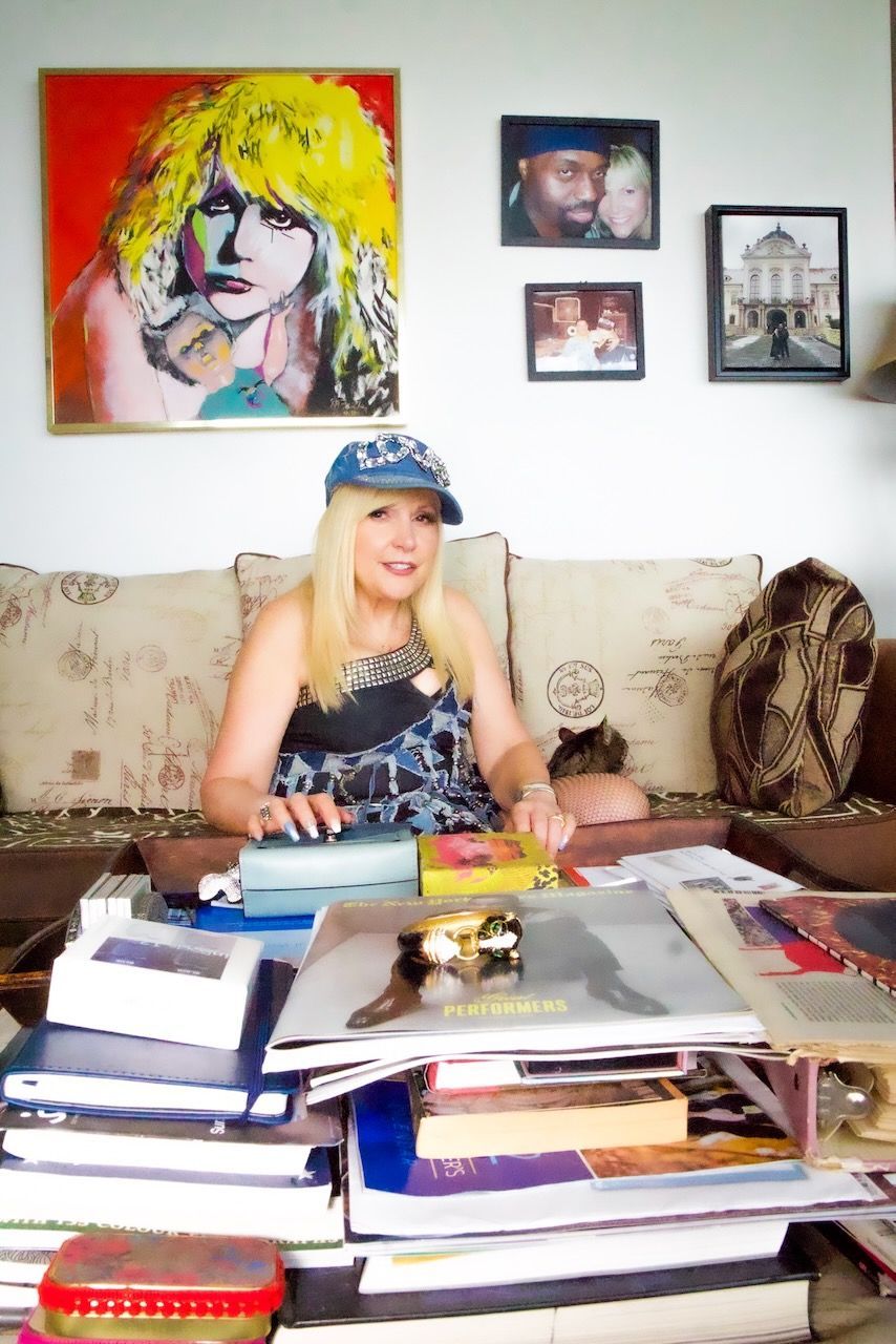 A woman is sitting on a couch next to a stack of books