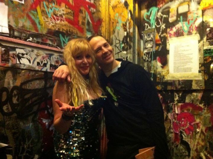 A man and a woman are posing for a picture in a room with graffiti on the wall.