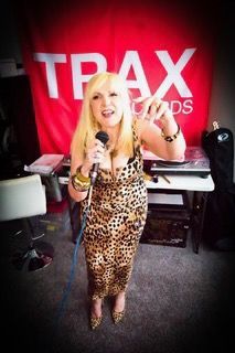 A woman in a leopard print dress is singing into a microphone in front of a trax records banner
