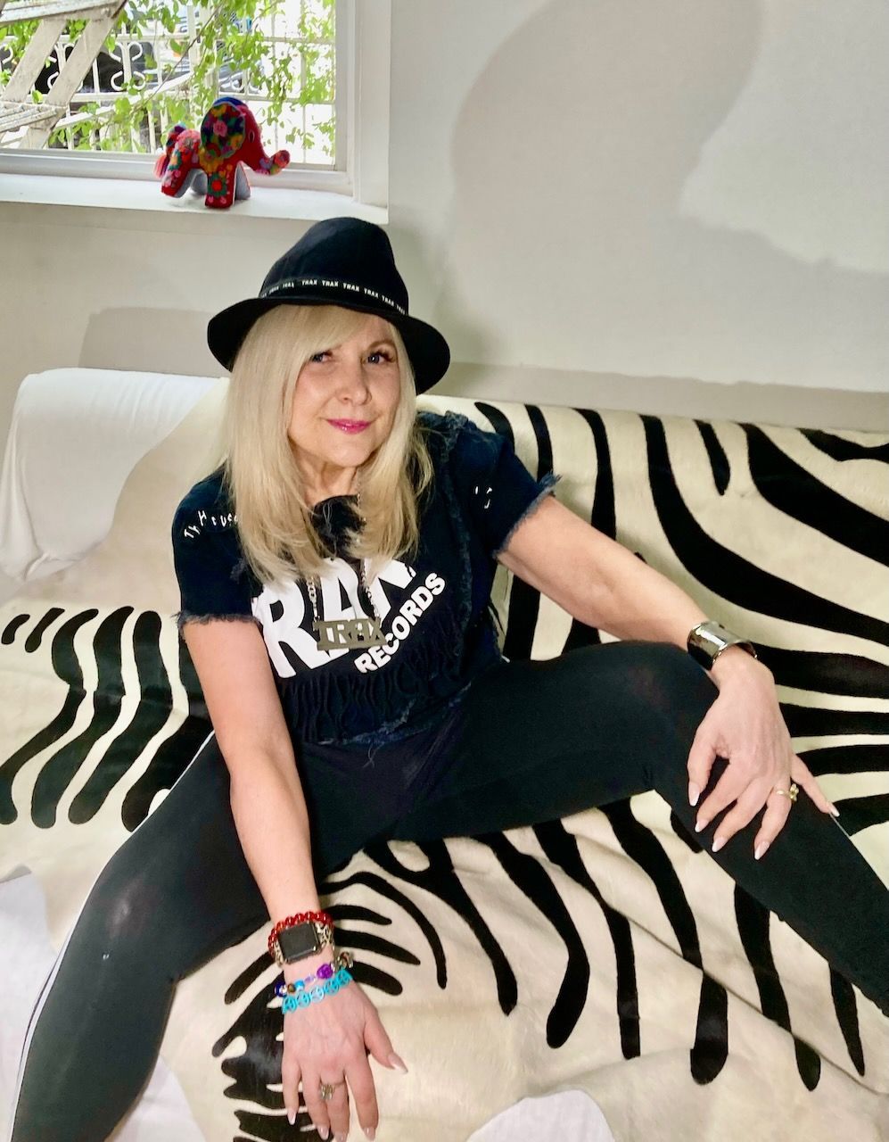 A woman wearing a hat is sitting on a zebra print couch.