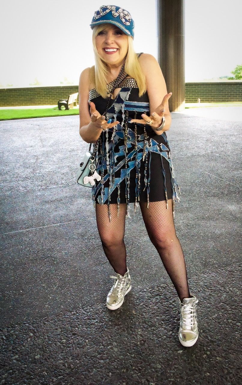 A woman wearing a hat and a dress is standing on the street.