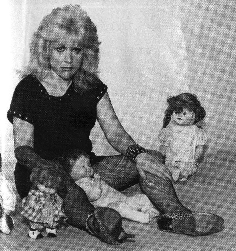 A woman is sitting on the floor holding two dolls