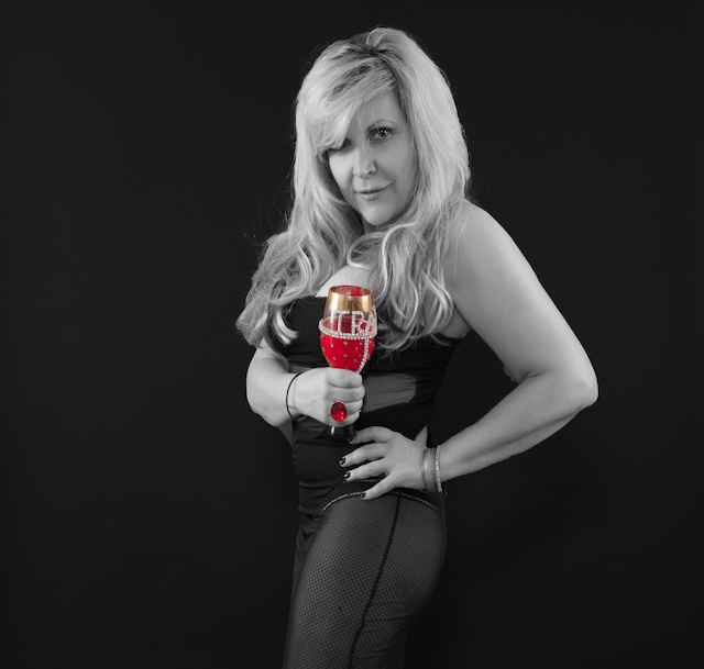A woman in a black dress is holding a glass of wine