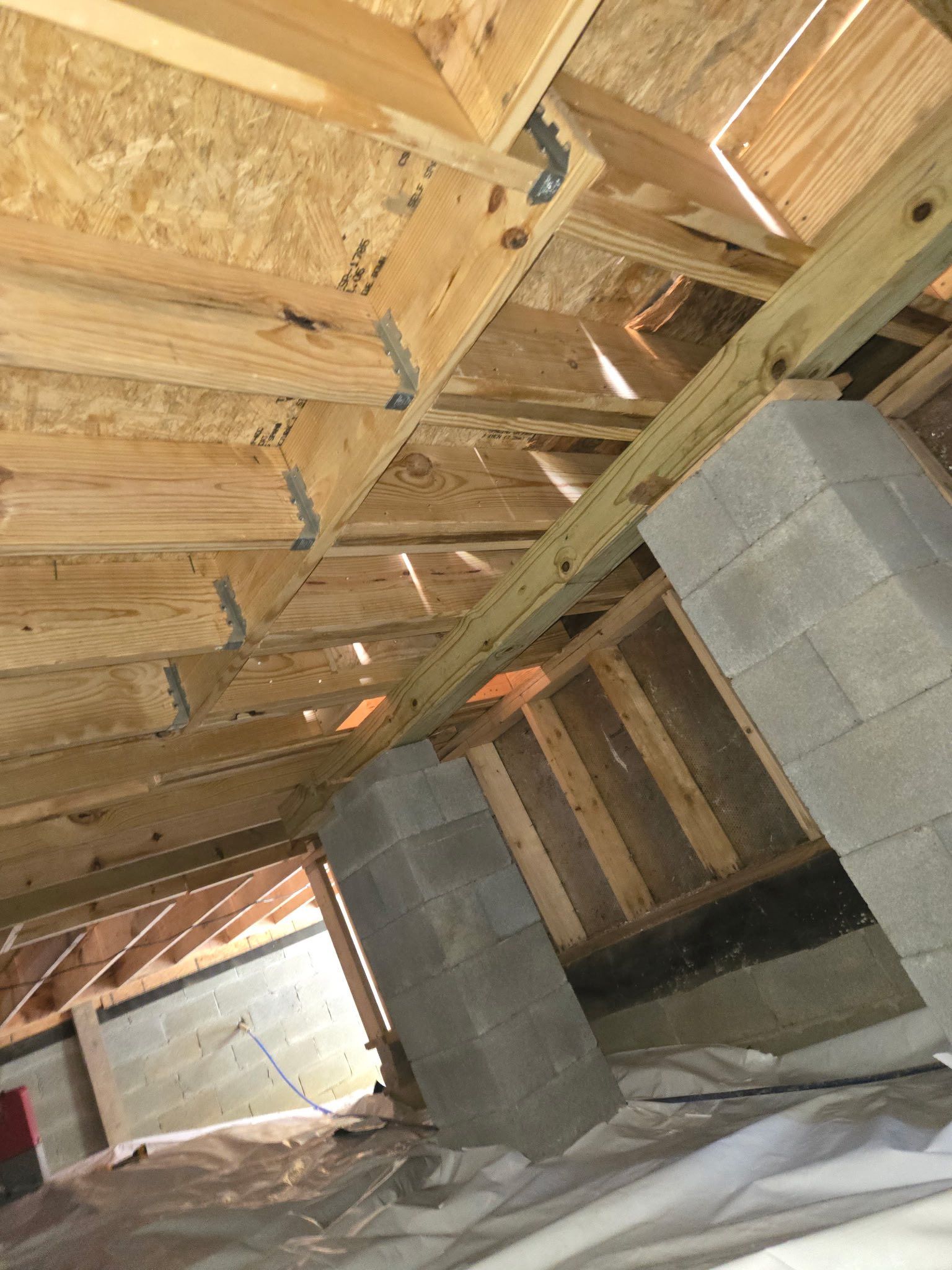 Unfinished attic with exposed wooden rafters, insulation boards, and construction materials on the floor. Unfinished attic with exposed wooden rafters, insulation boards, and construction materials on the floor.