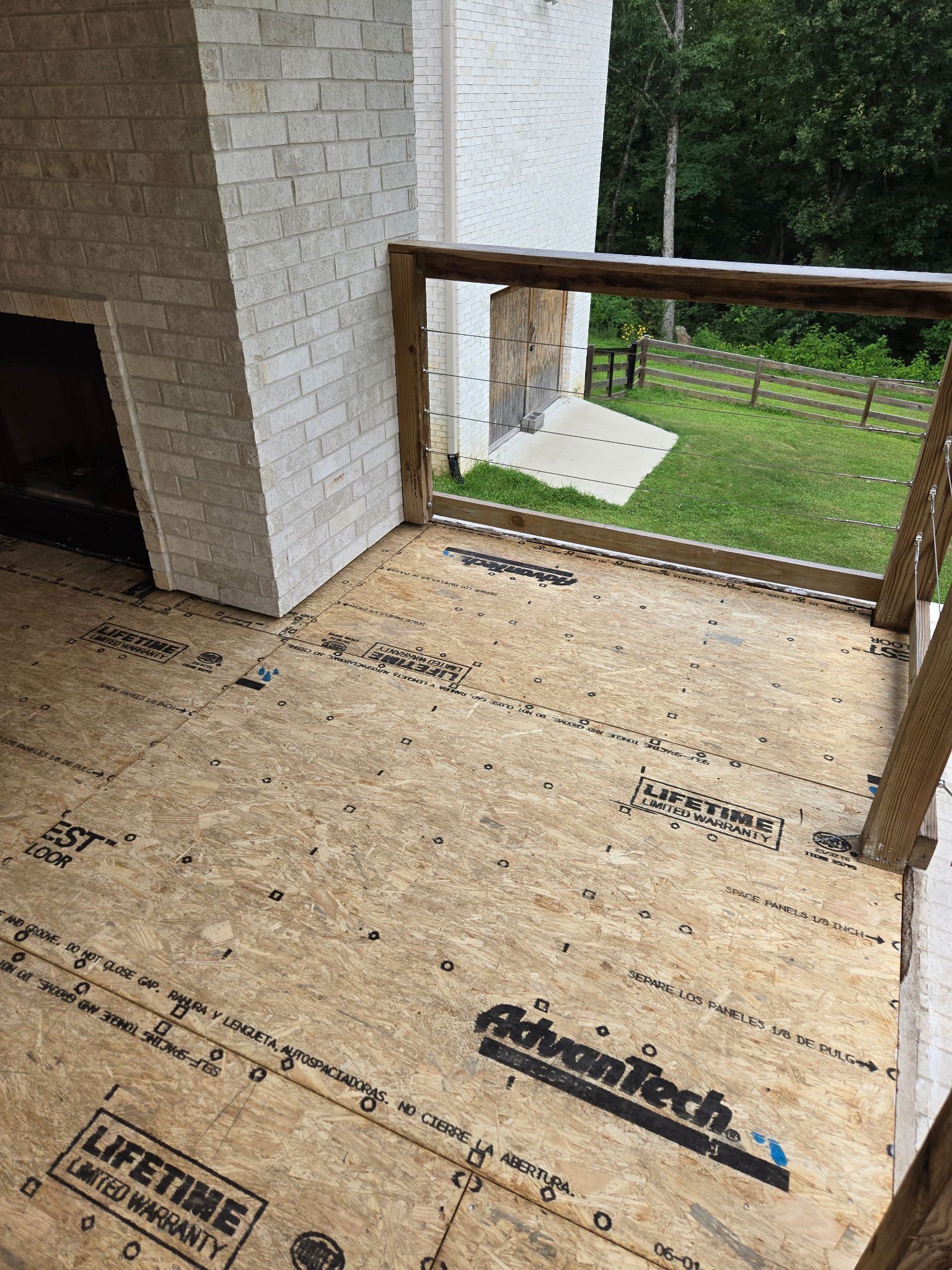 Wood-framed balcony under construction with plywood flooring and a white brick wall. Wood-framed balcony under construction with plywood flooring and a white brick wall.