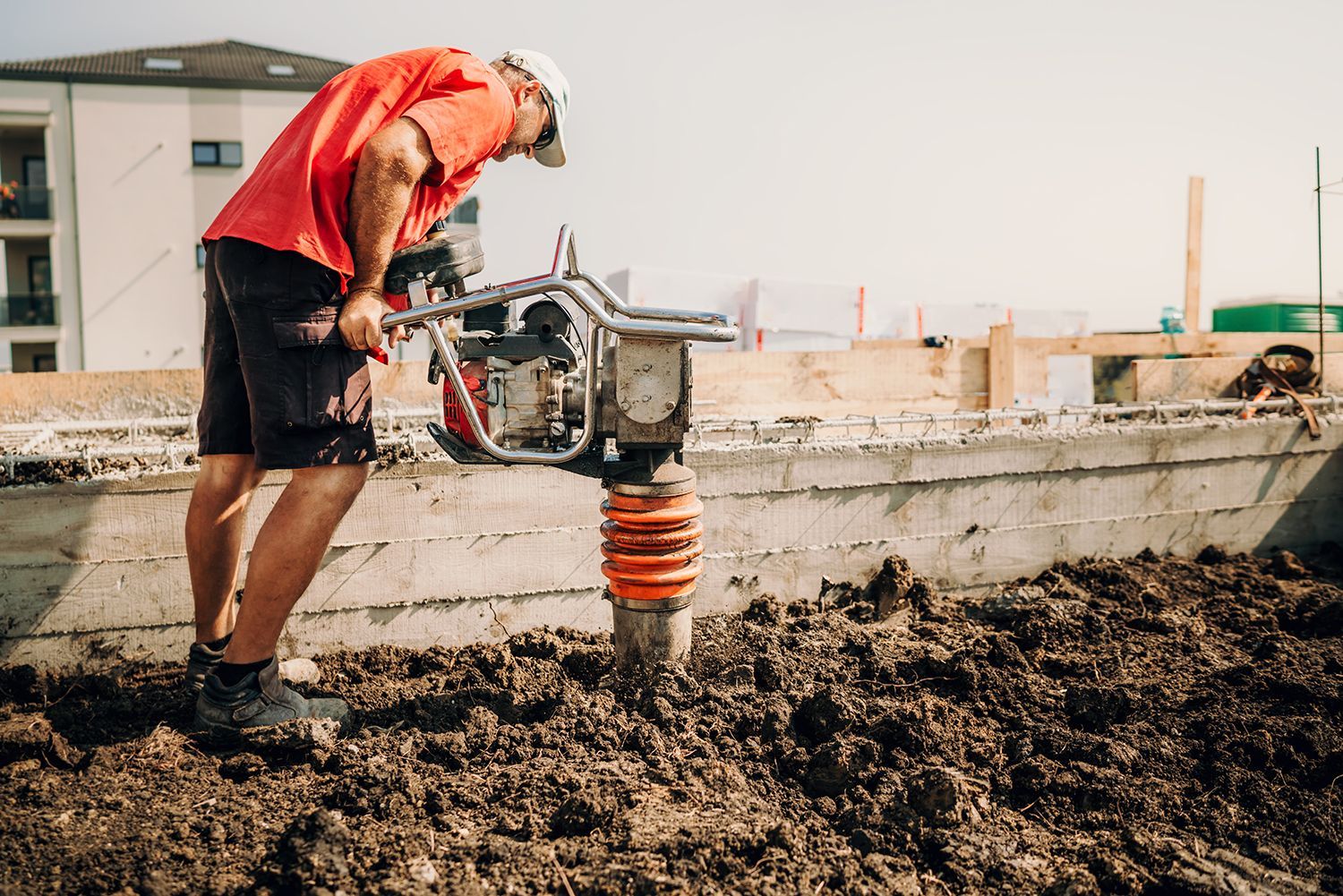 Worker in a red shirt operating a jackhammer on a construction site Worker in a red shirt operating a jackhammer on a construction site