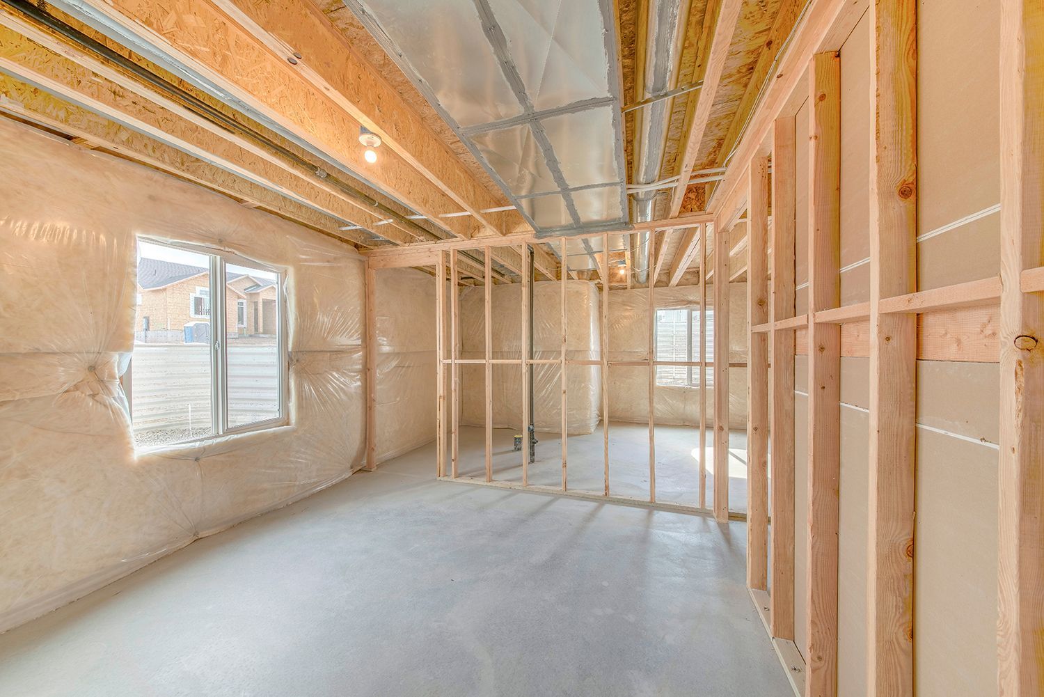 Unfinished room with exposed wooden framing, insulation, concrete floor, and a window on the left. Unfinished room with exposed wooden framing, insulation, concrete floor, and a window on the left.