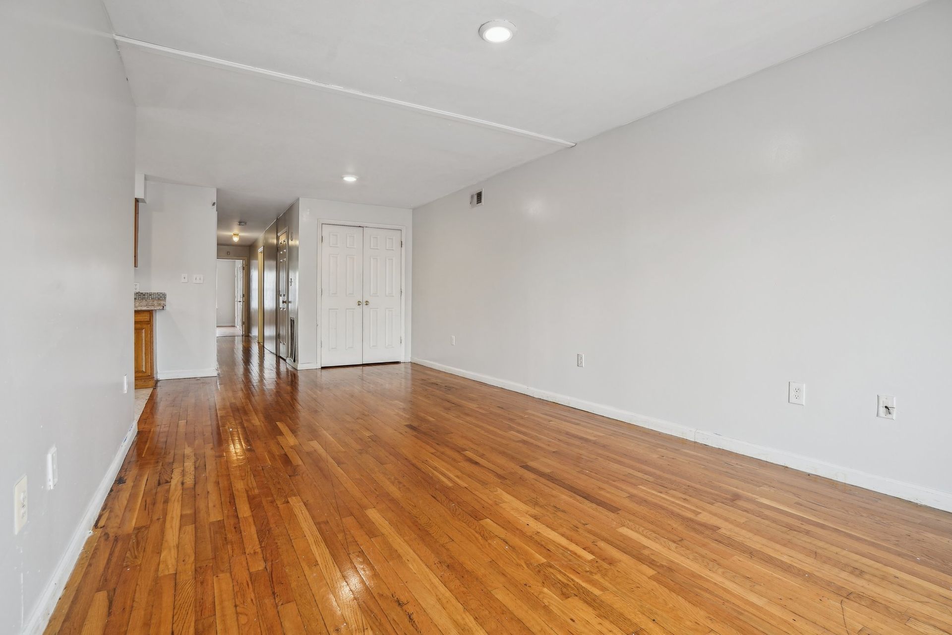 Empty room with hardwood floors, white walls, and a closed door.