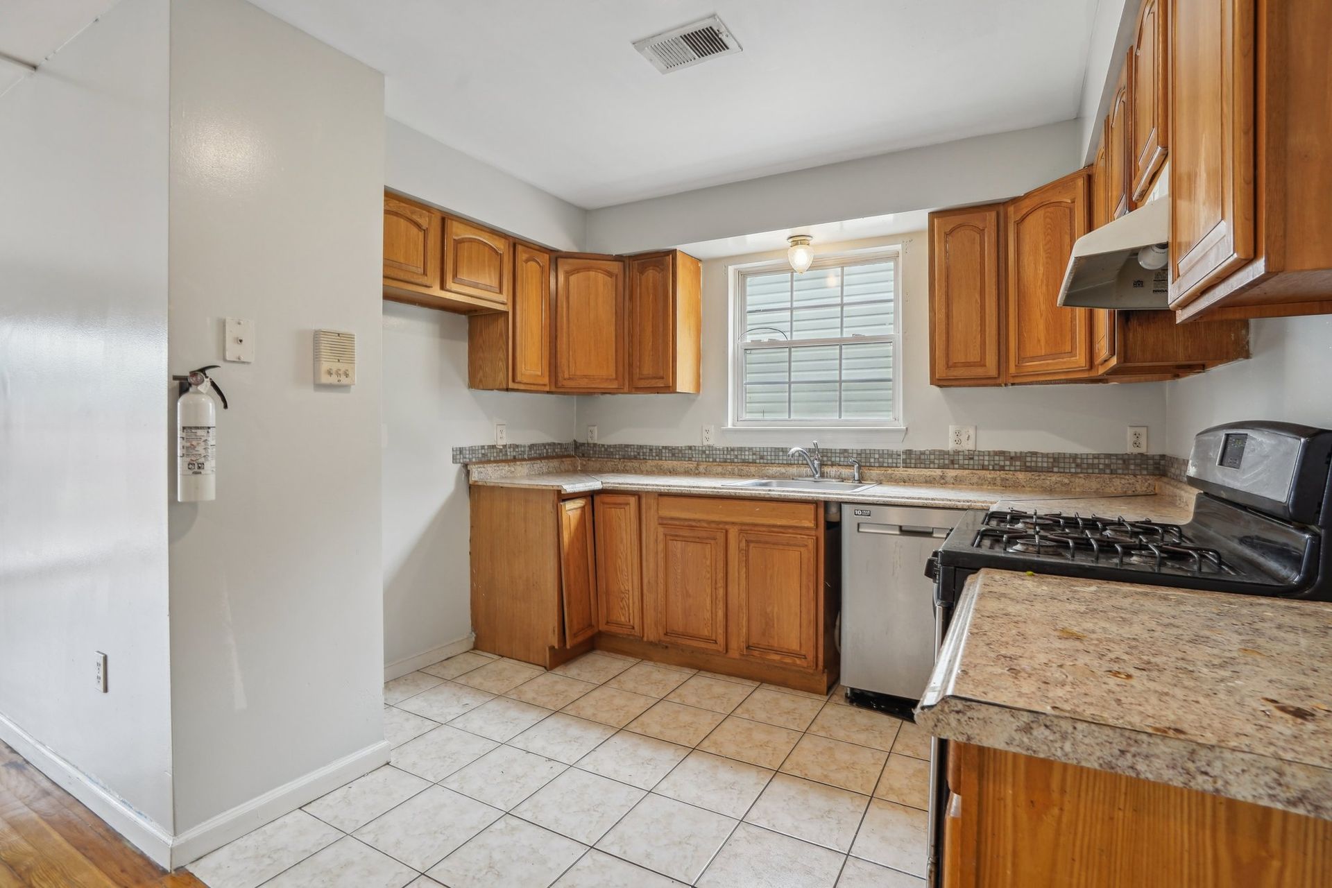 Kitchen with light wood cabinets, granite countertops, and white tile floor.