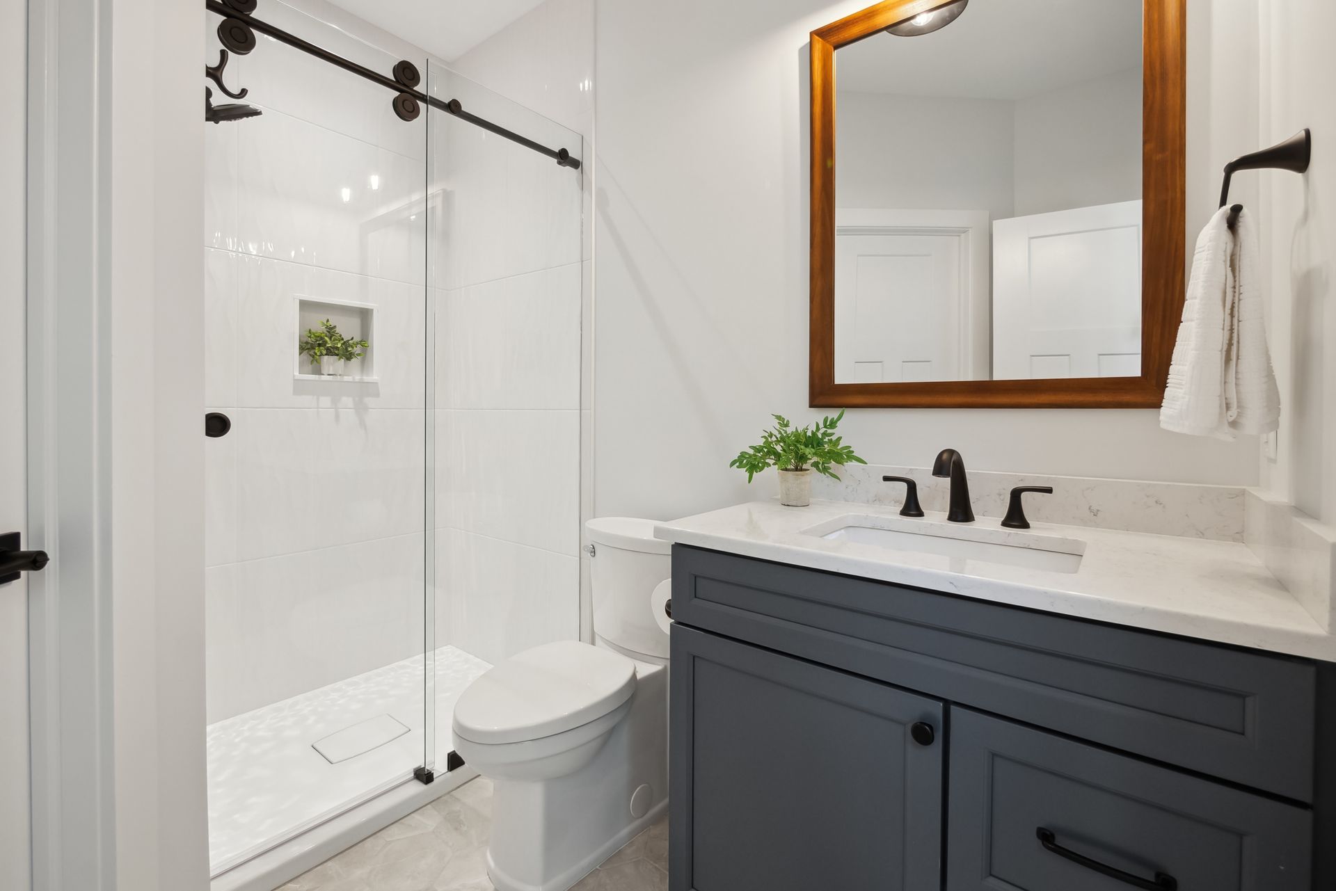 Modern bathroom with a gray vanity, white walls, and a glass shower door.