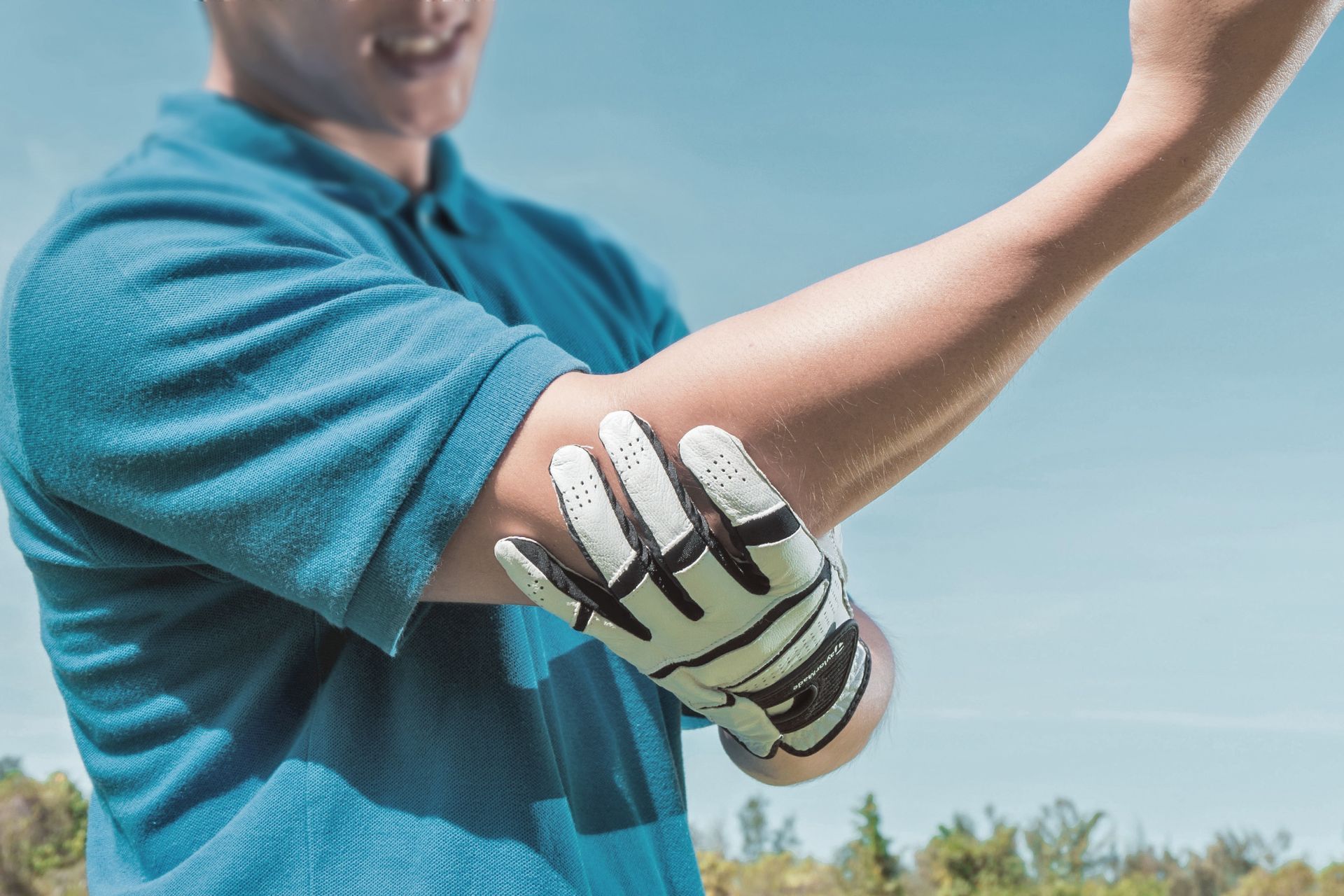 athlete holding elbow with gloved hand