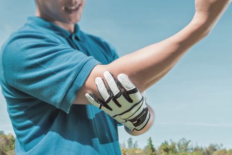 athlete holding elbow with gloved hand