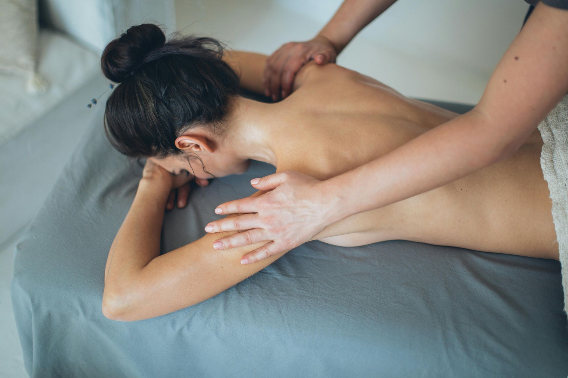 A woman is laying on a bed getting a massage.