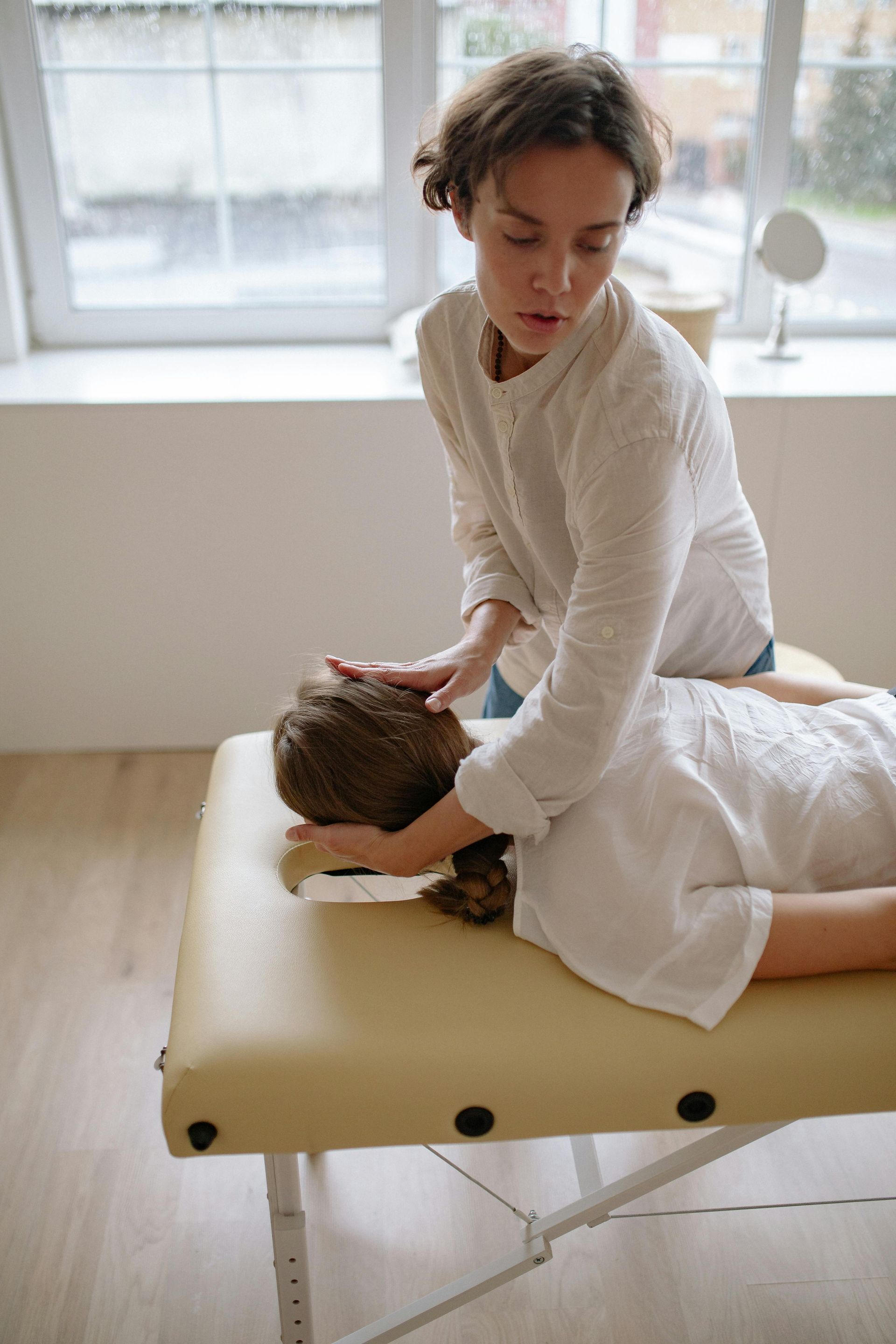 A woman is giving a child a massage on a table.