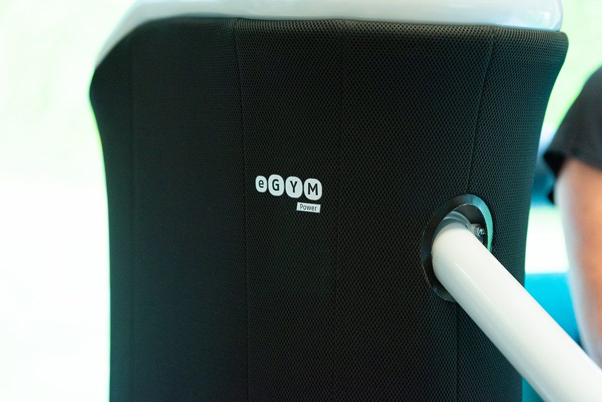 Een persoon staat naast een zwarte stoel met een witte paal eraan.