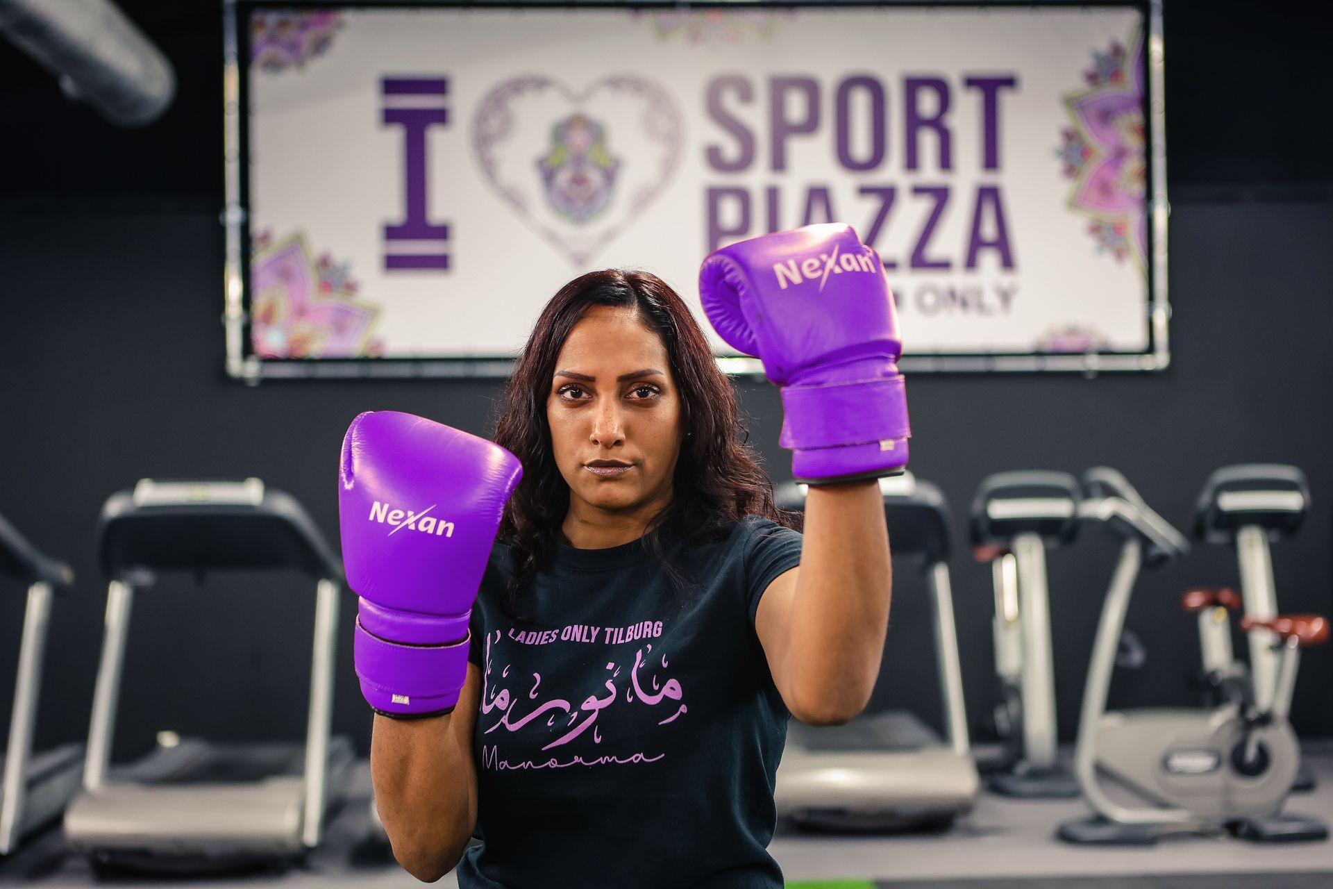Een vrouw draagt ​​paarse bokshandschoenen in een sportschool.