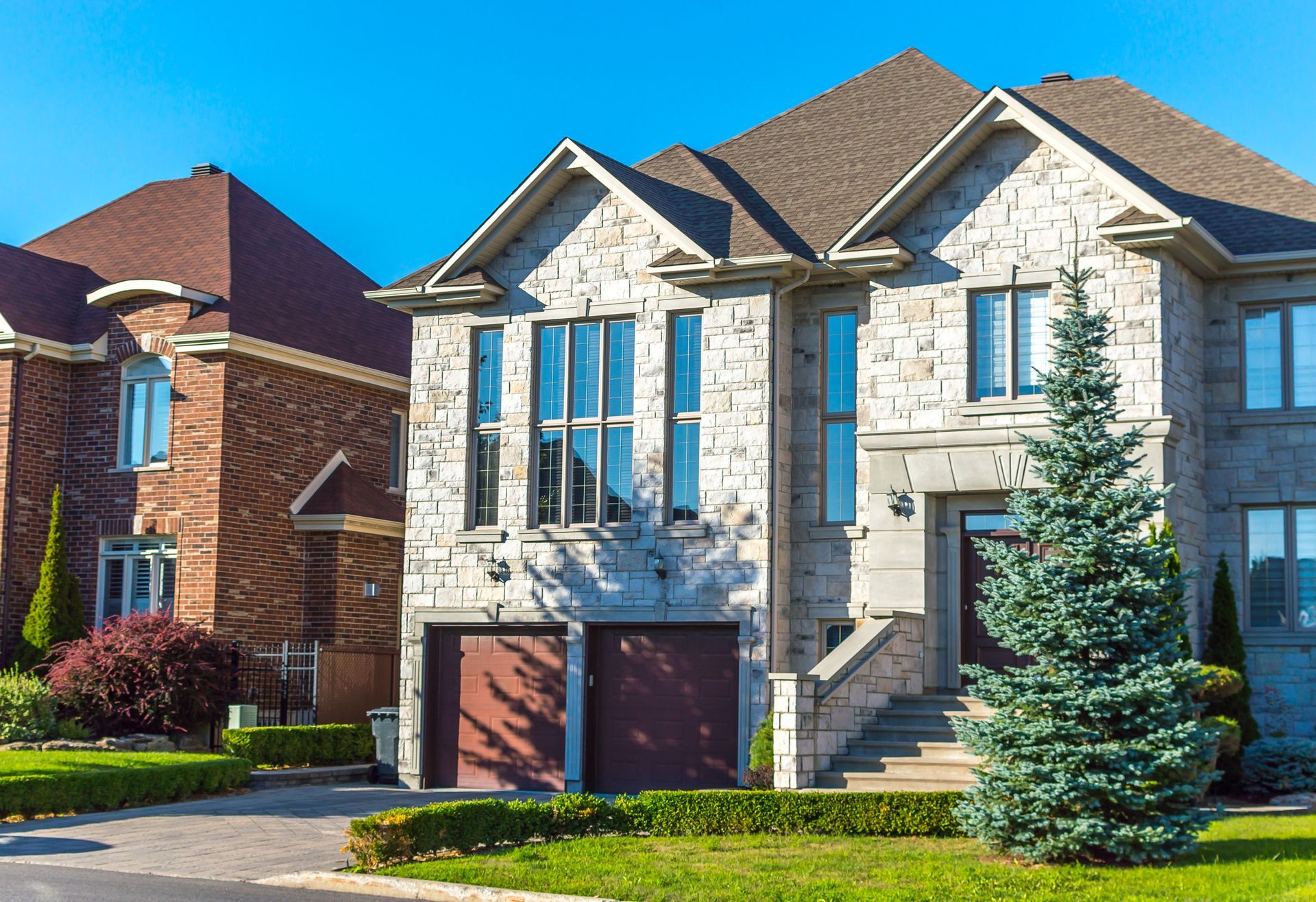 A large brick house with a garage and stairs in front of it.