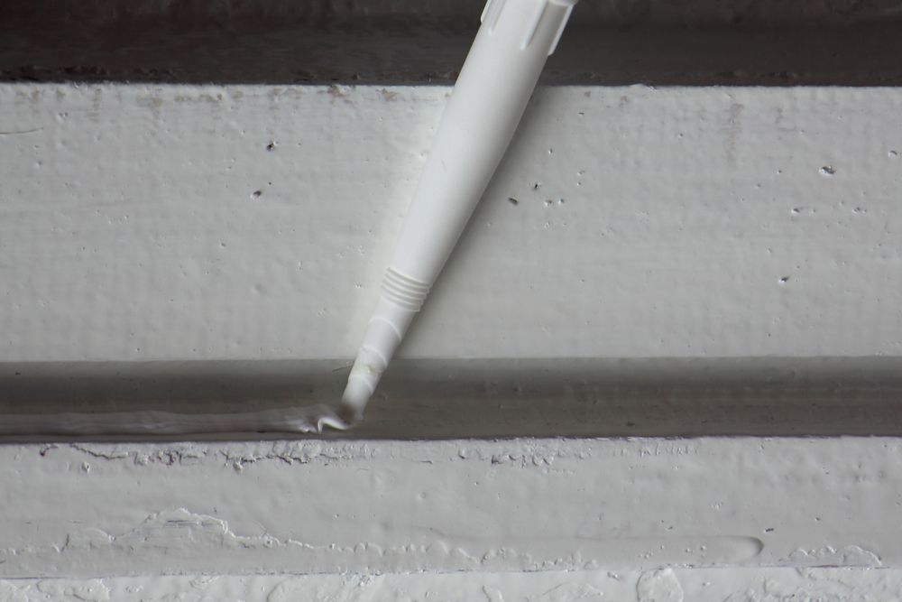 Un stylo blanc est utilisé pour combler un trou dans un mur blanc.