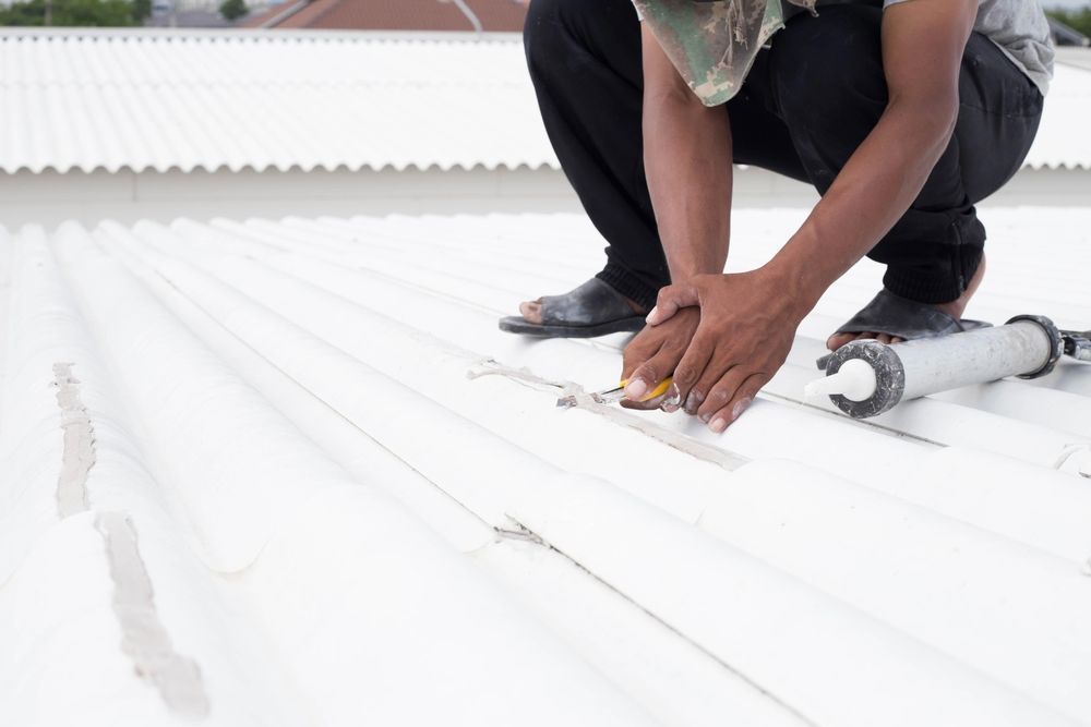 A man is kneeling on the roof of a building.