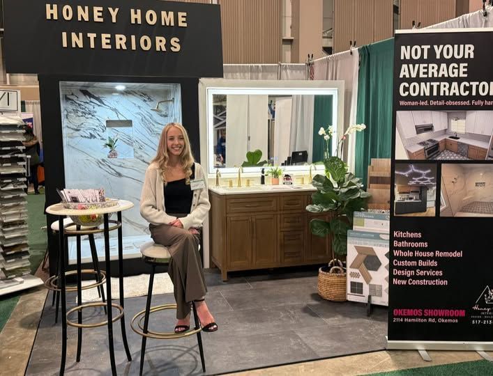 Woman with long blonde hair, smiling, standing in front of blue tile wall and white cabinets.