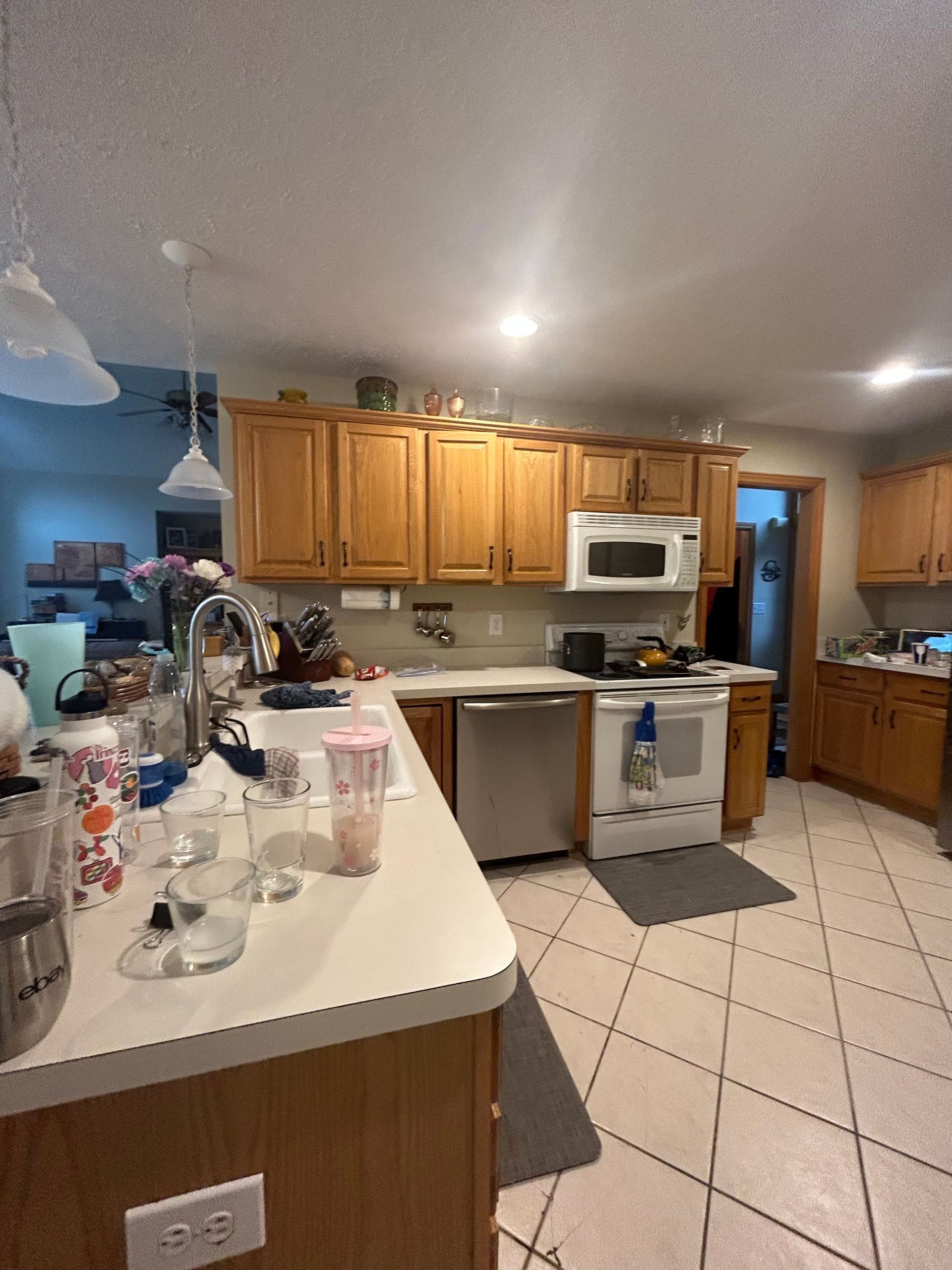 Kitchen with light-colored wood cabinets, white appliances, and tiled floors.