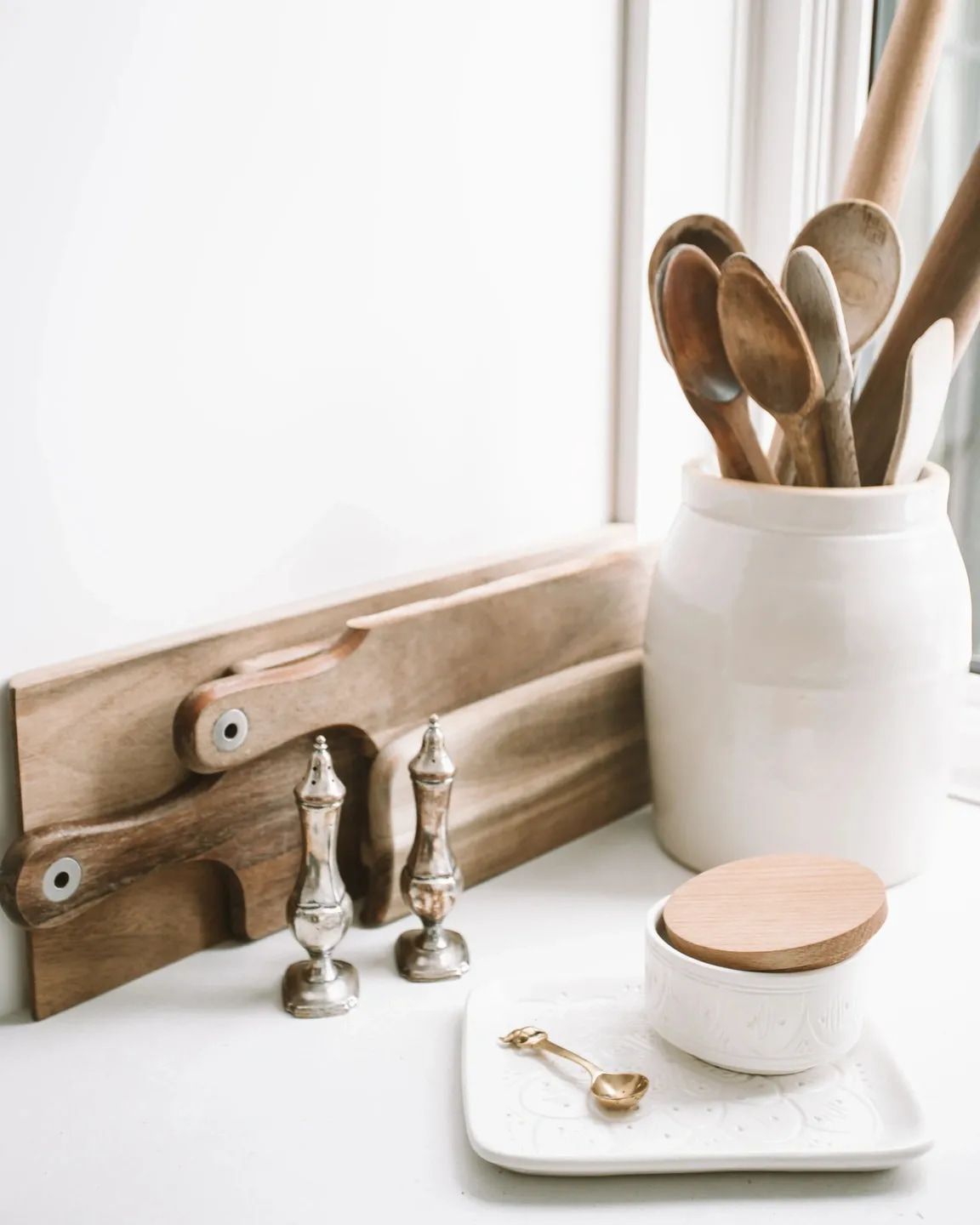 A jar filled with wooden spoons and salt and pepper shakers on a table.