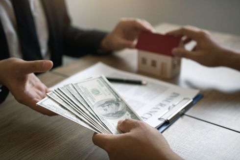 A person is handing a stack of money to another person.