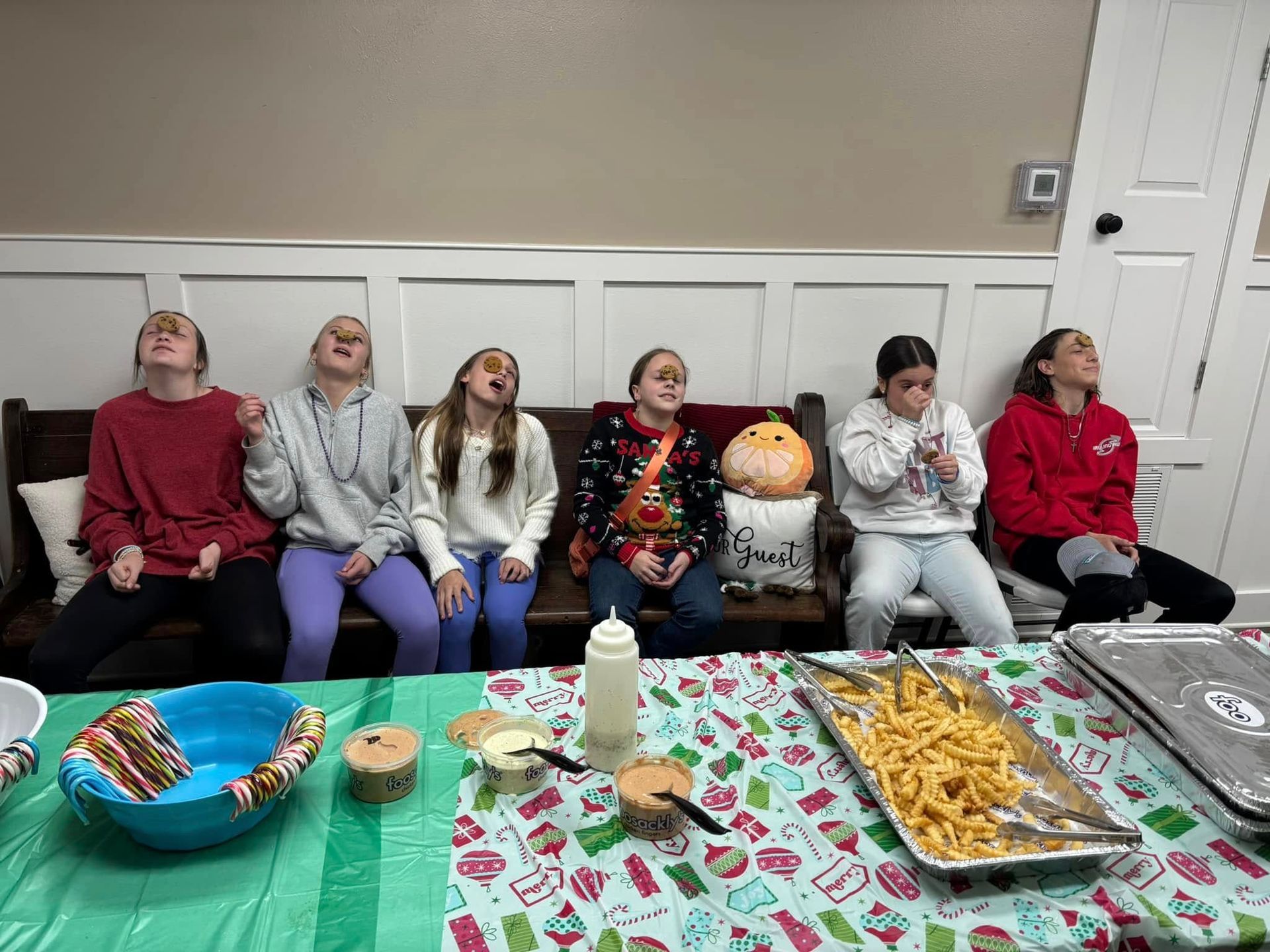 Six people looking up, seated on a bench, near a table with food.
