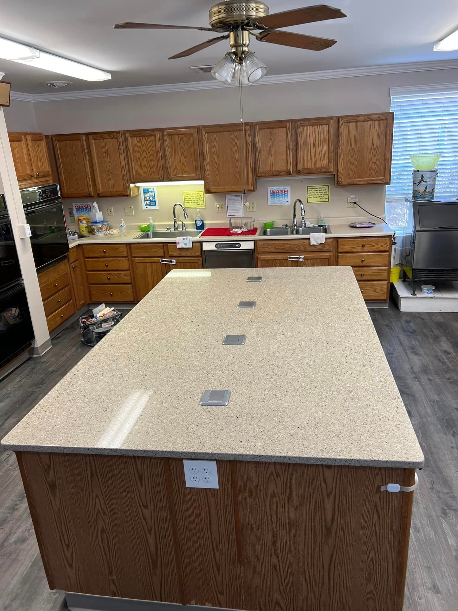 A kitchen with a large island and a ceiling fan.