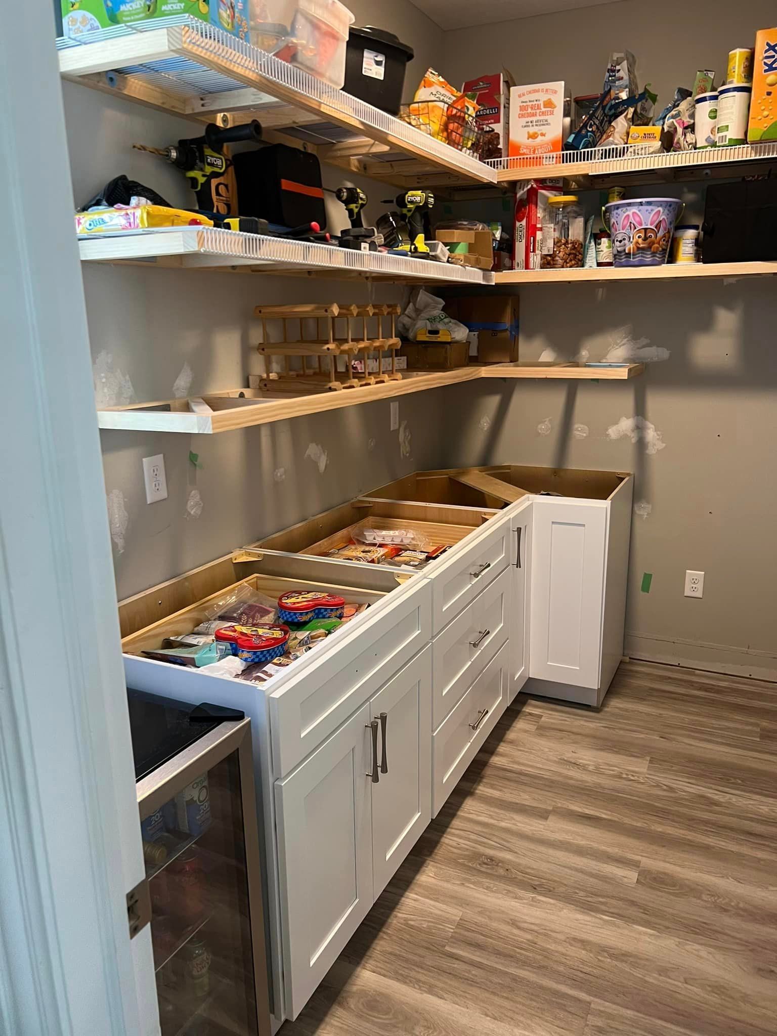 A pantry with white cabinets and shelves filled with food.