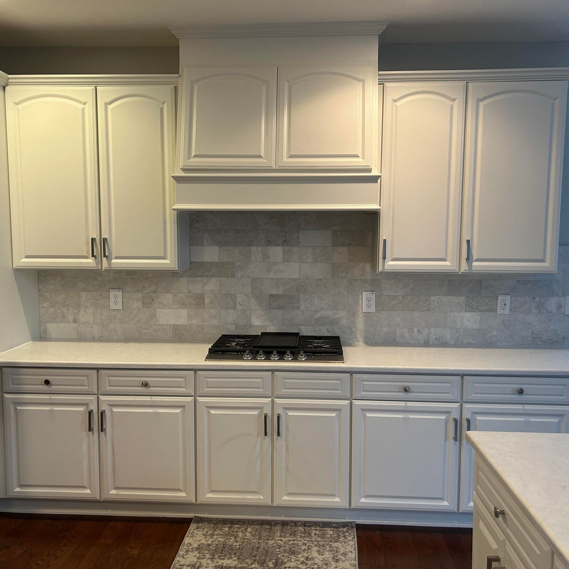 A kitchen with white cabinets and a stove top oven.