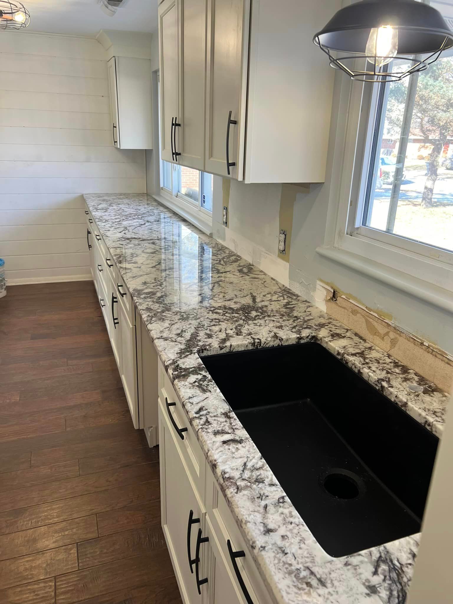 A kitchen with granite counter tops and a black sink.