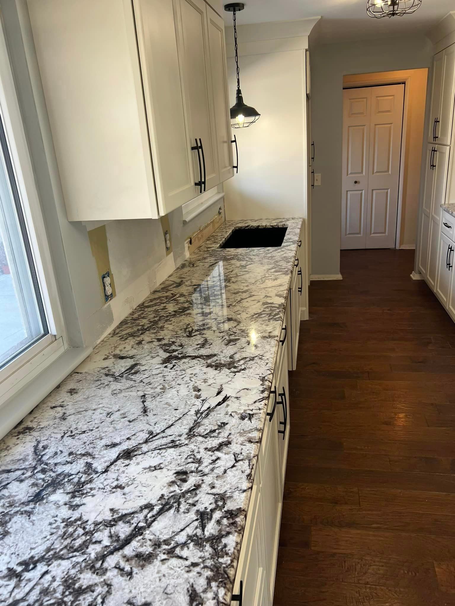 A kitchen with granite counter tops and white cabinets.