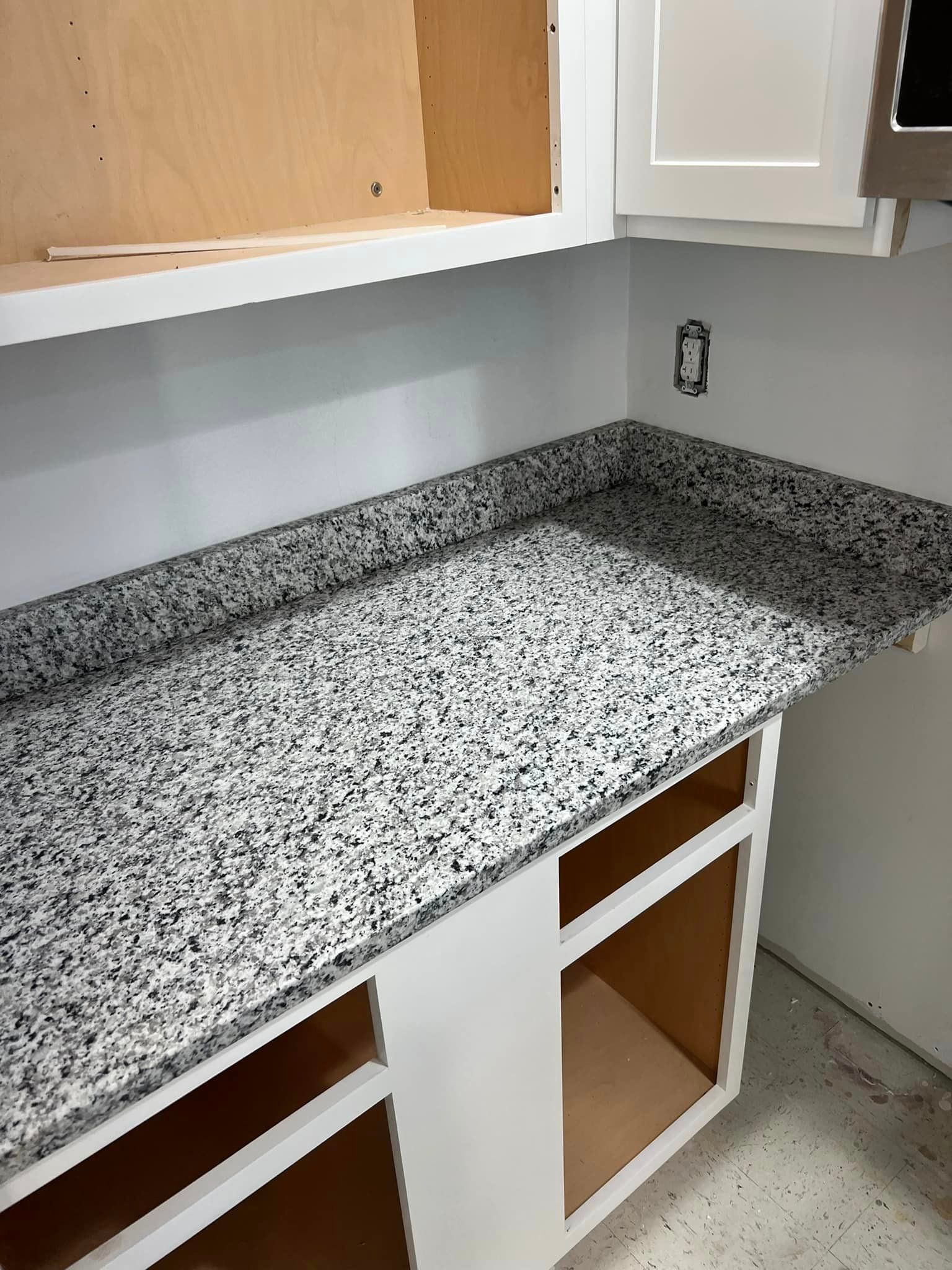 A kitchen with a granite counter top and white cabinets