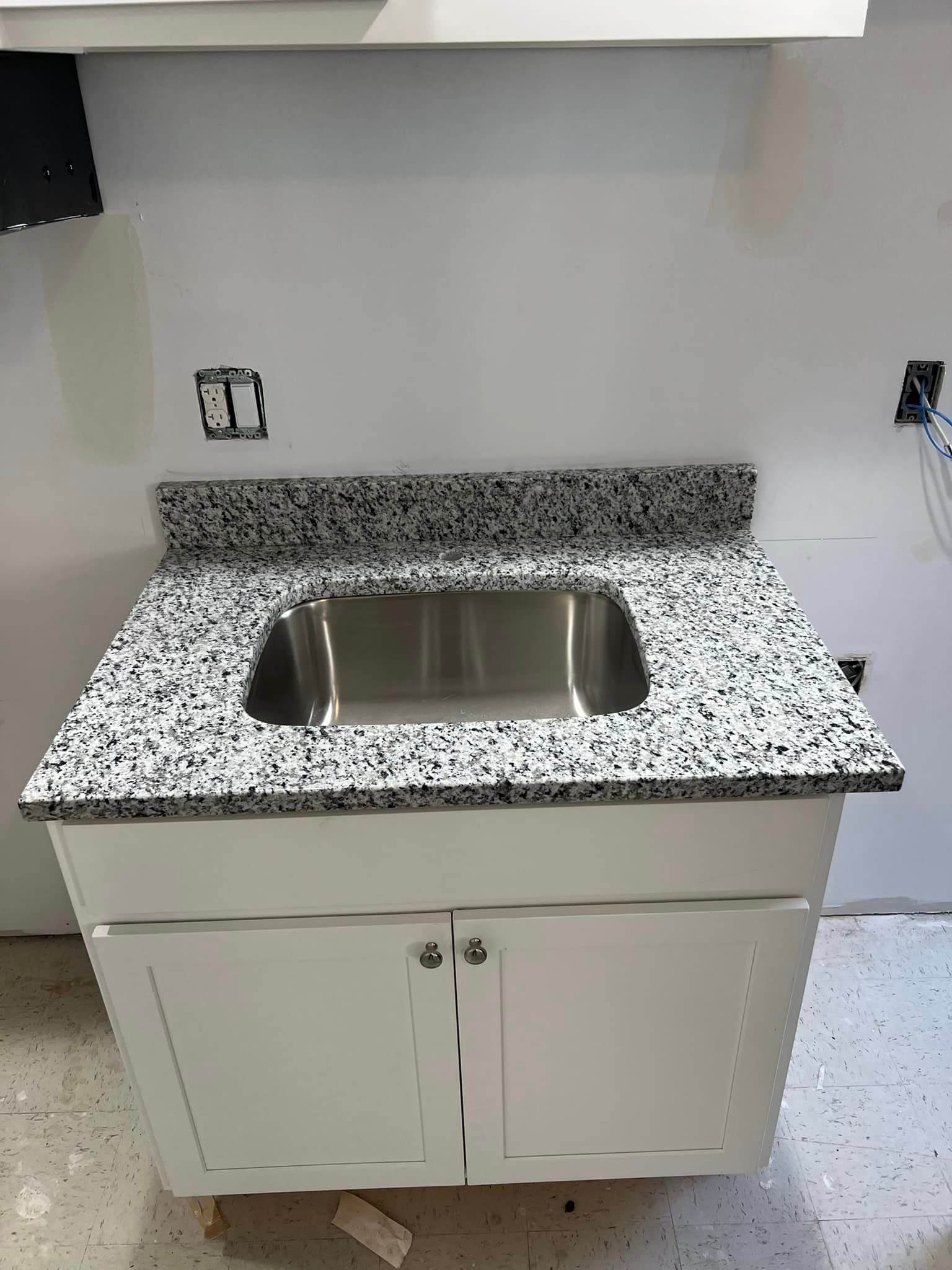 A kitchen sink is sitting on top of a granite counter top.