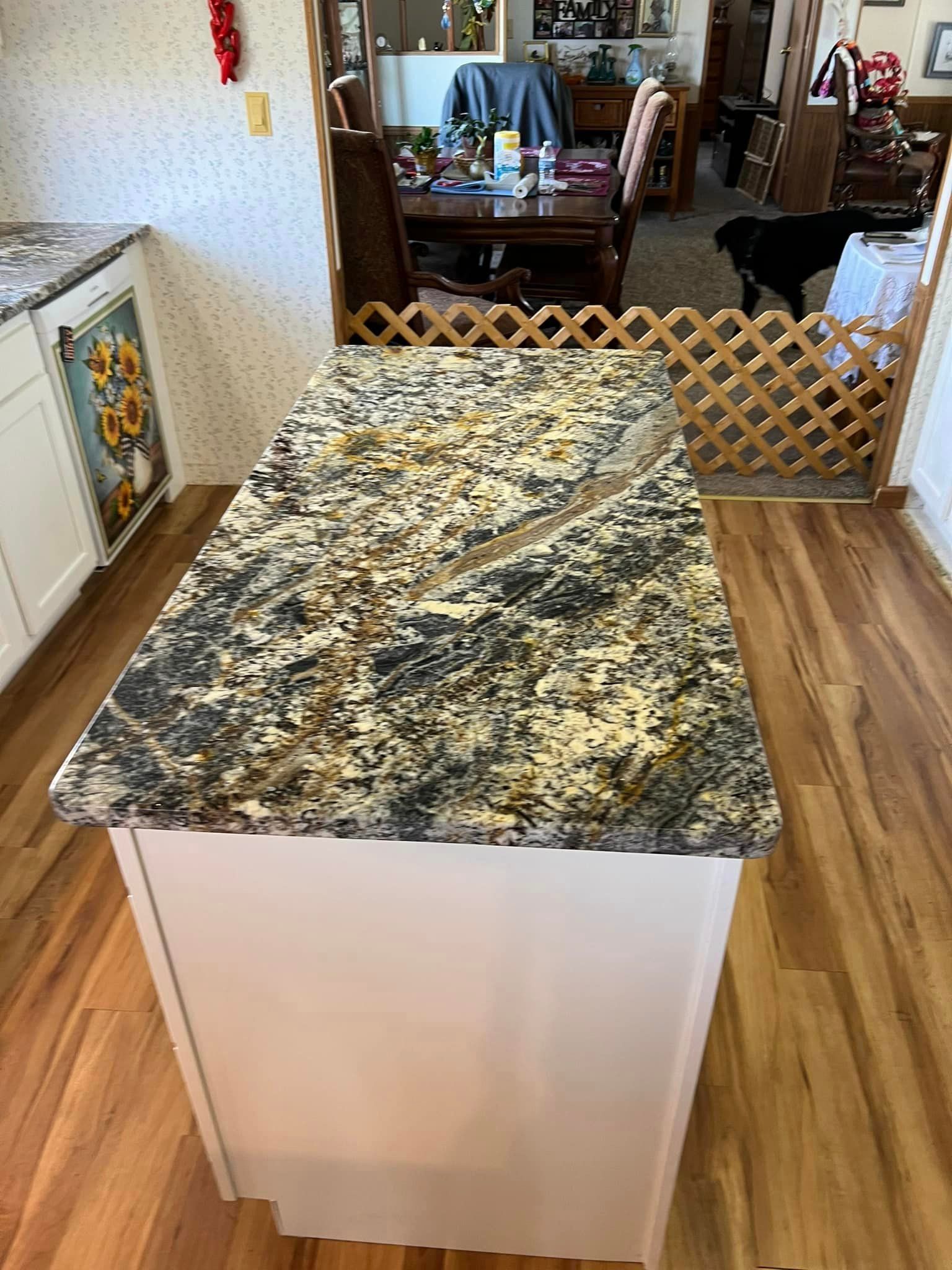 A kitchen island with a granite counter top and a wooden floor.