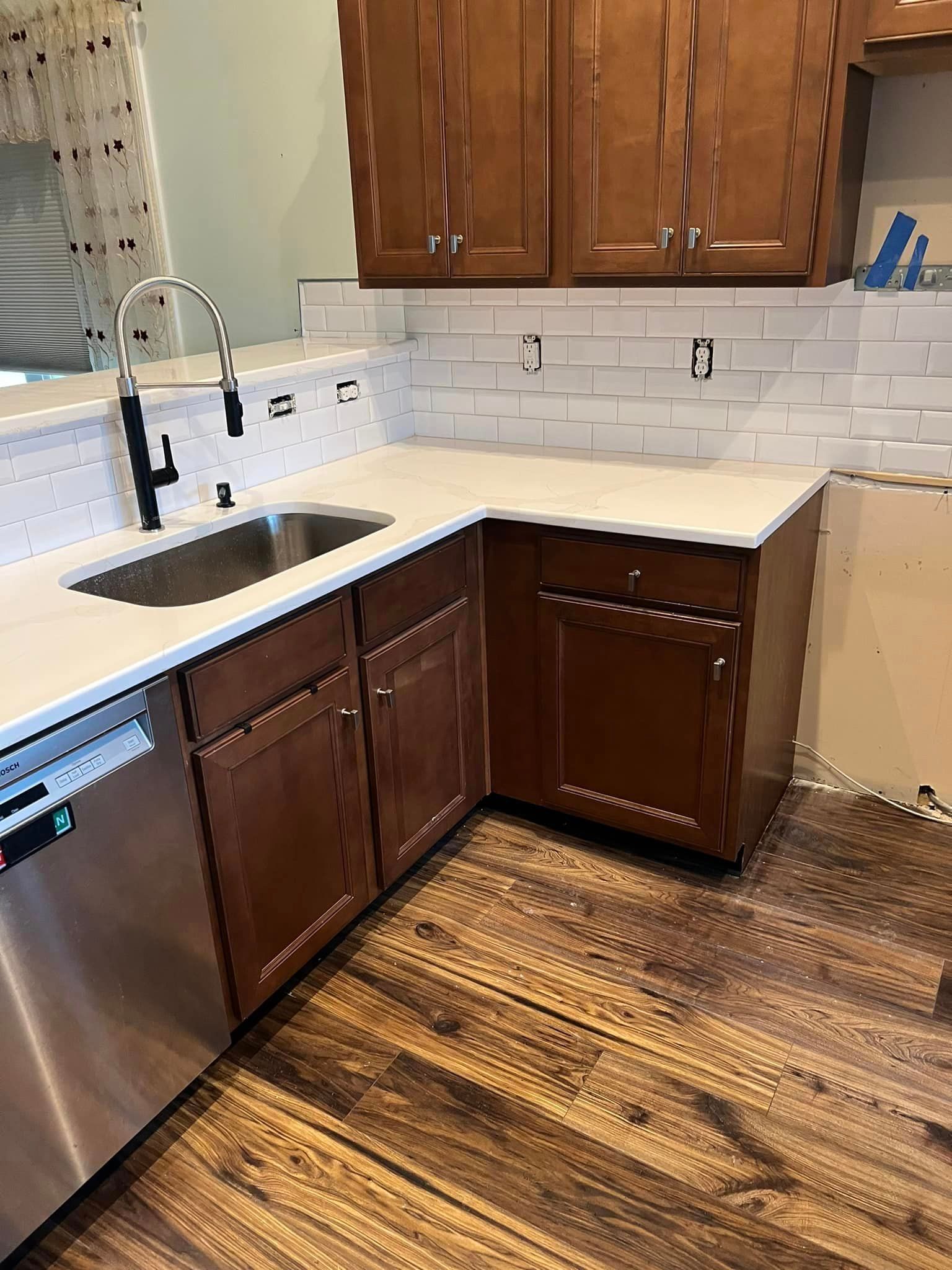 A kitchen with wooden cabinets , stainless steel appliances , and a sink.