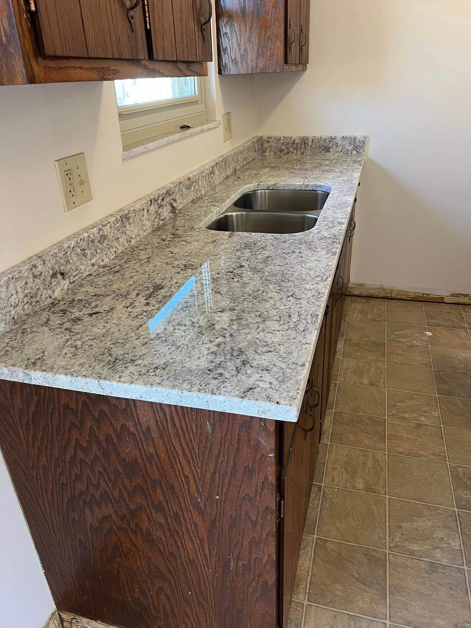 A kitchen with a granite counter top and two sinks.