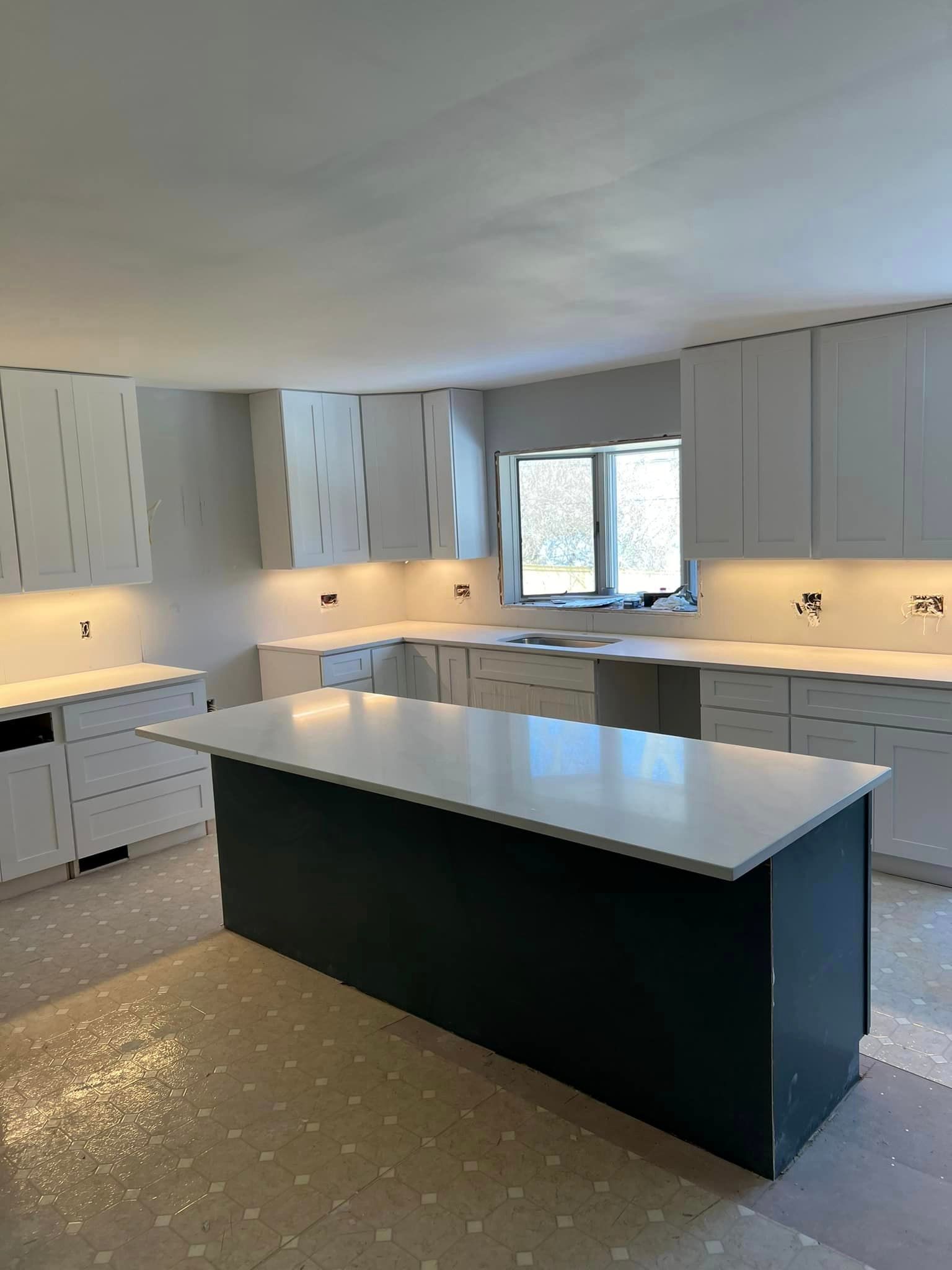 A kitchen with white cabinets and a large island in the middle.