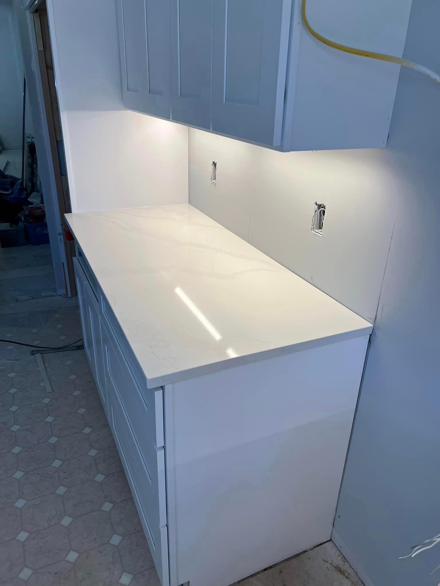 A kitchen with white cabinets and a white counter top.