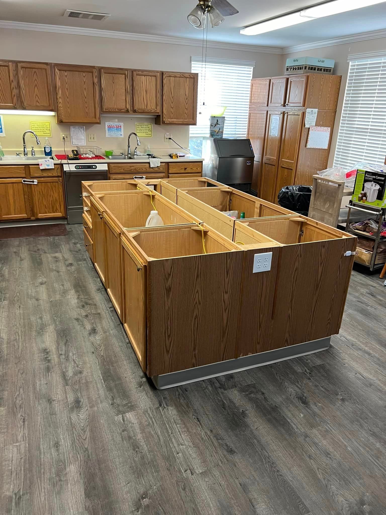 A kitchen with wooden cabinets and a large wooden island in the middle of the room.