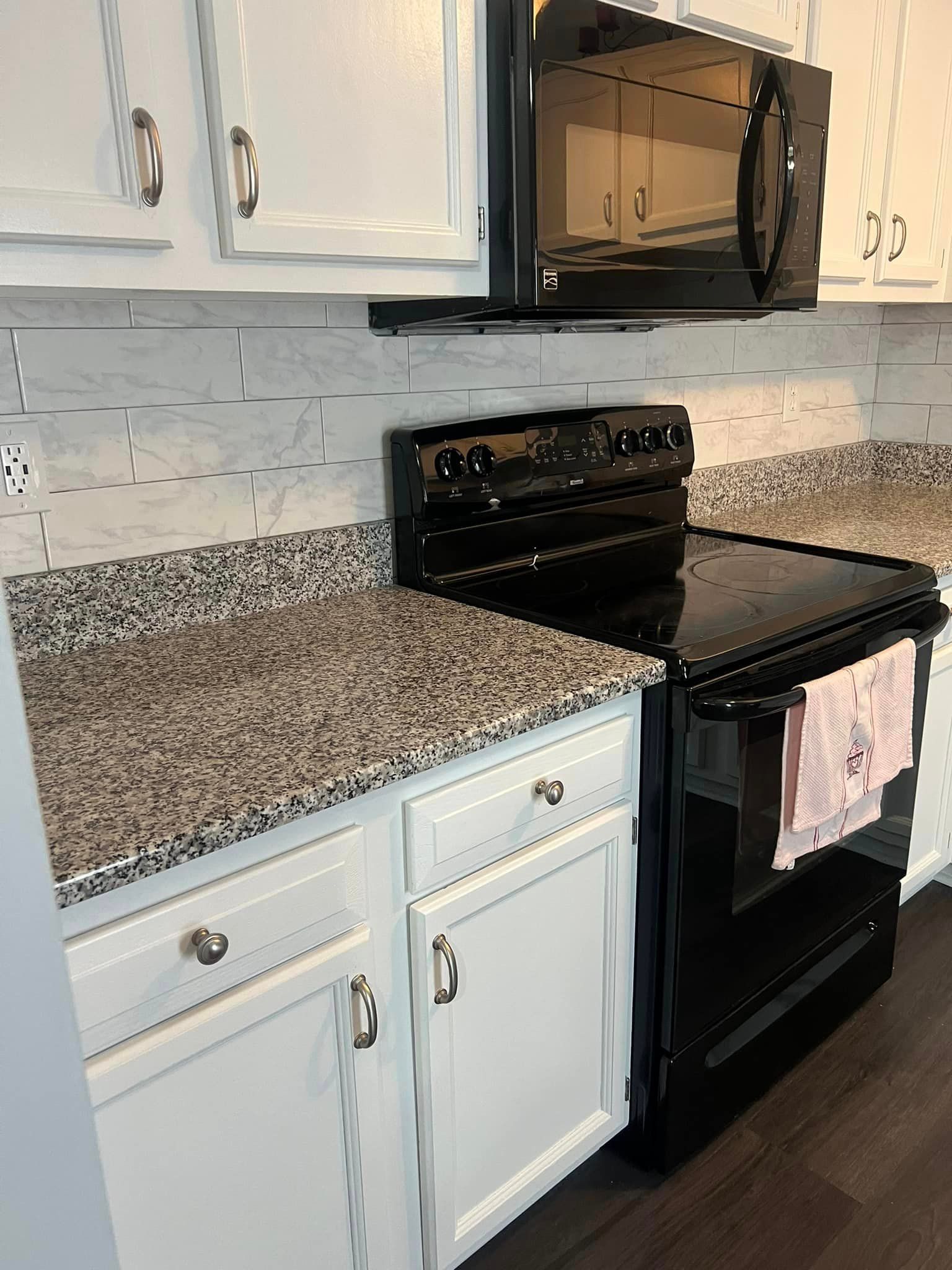 A kitchen with a stove , microwave , and granite counter tops.