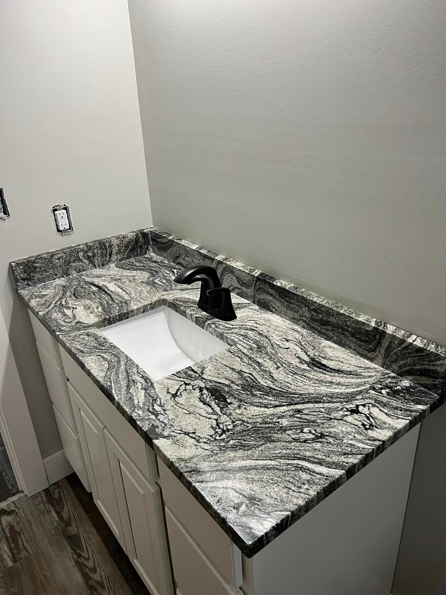 A bathroom vanity with a granite counter top and a sink.
