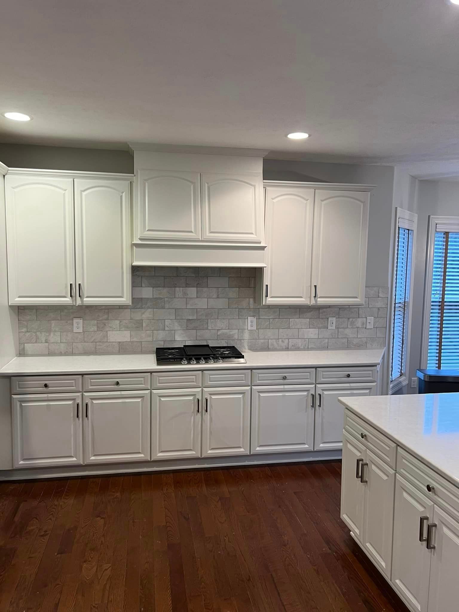 A kitchen with white cabinets , a stove , and a large island.
