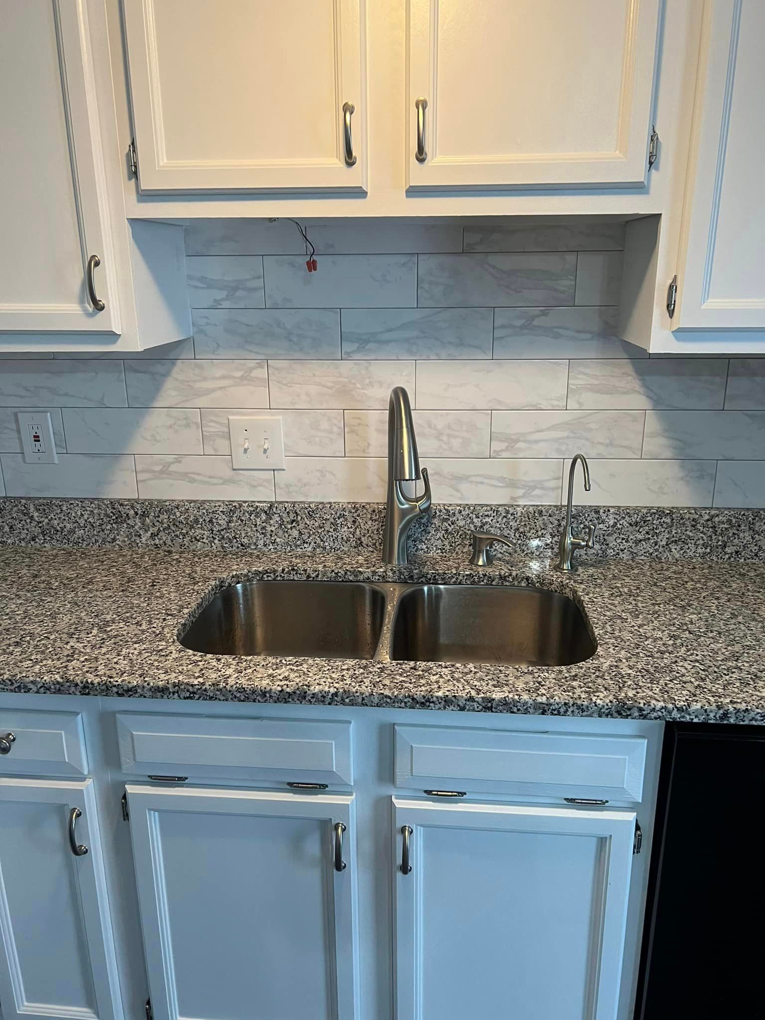 A kitchen with granite counter tops and a stainless steel sink.